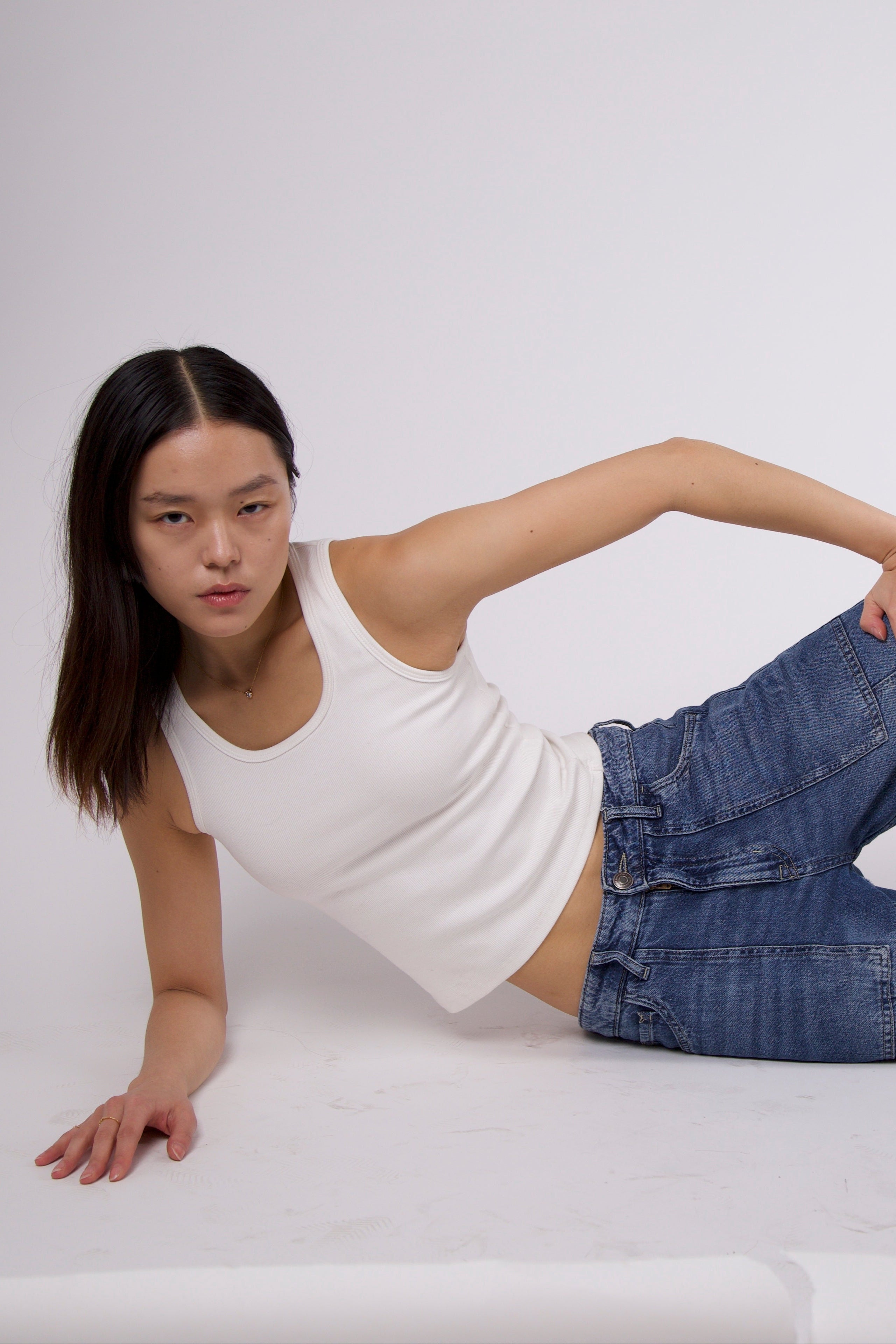 Model seated wearing white ribbed tank – minimalist, supportive everyday style